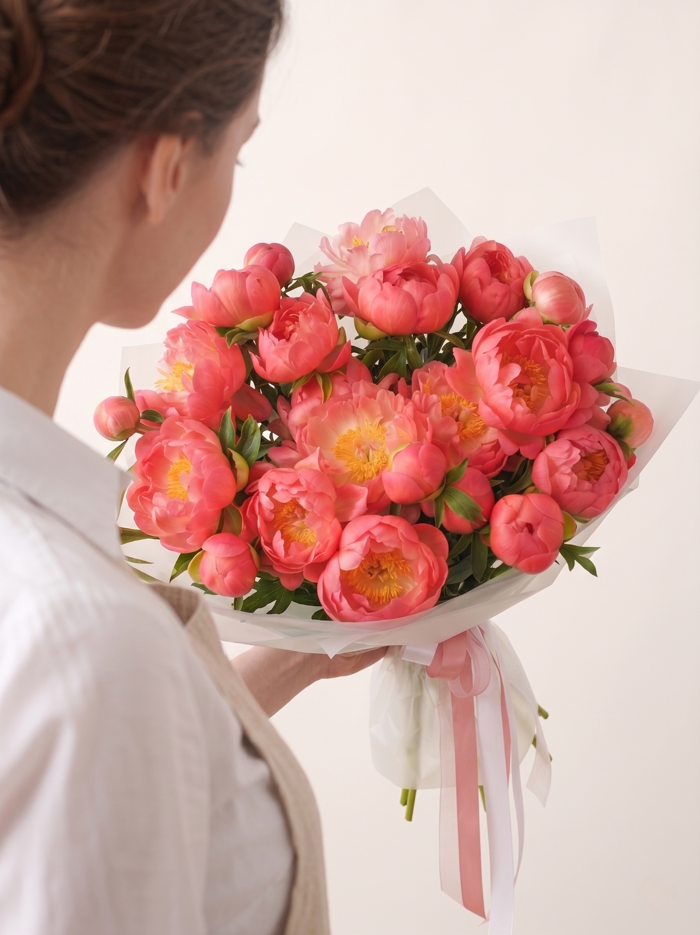 Person holding a bouquet of pink flowers with a white background