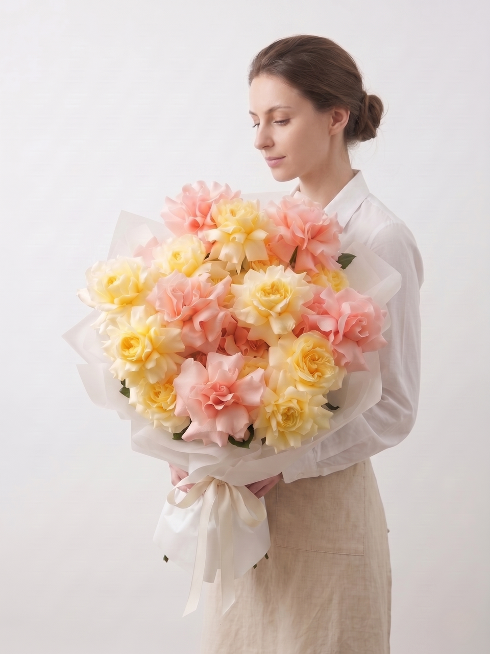 Woman holding a bouquet of pink and yellow flowers against a white background