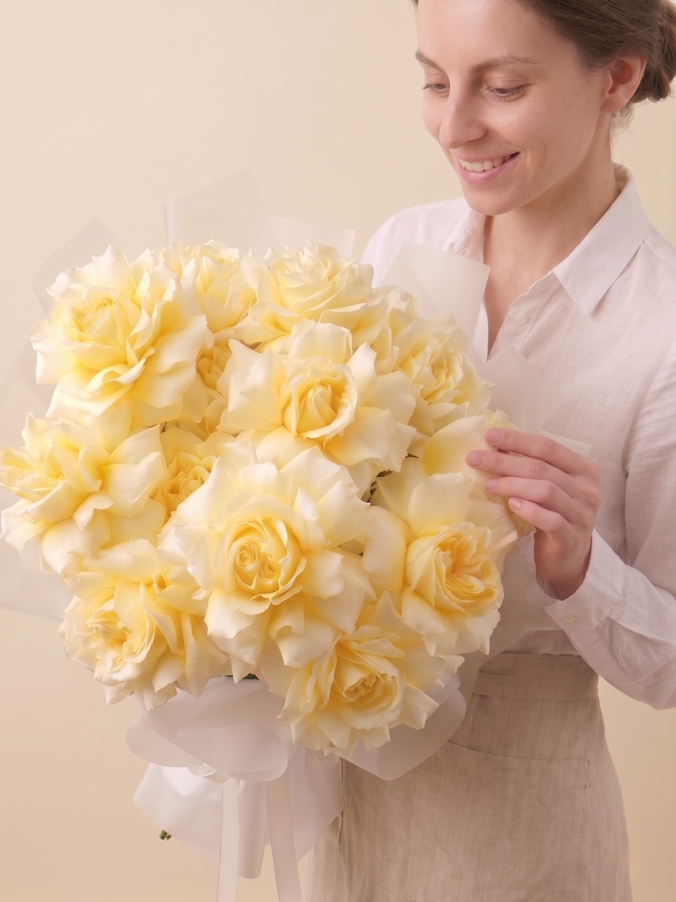 Woman holding a large bouquet of yellow flowers against a plain background