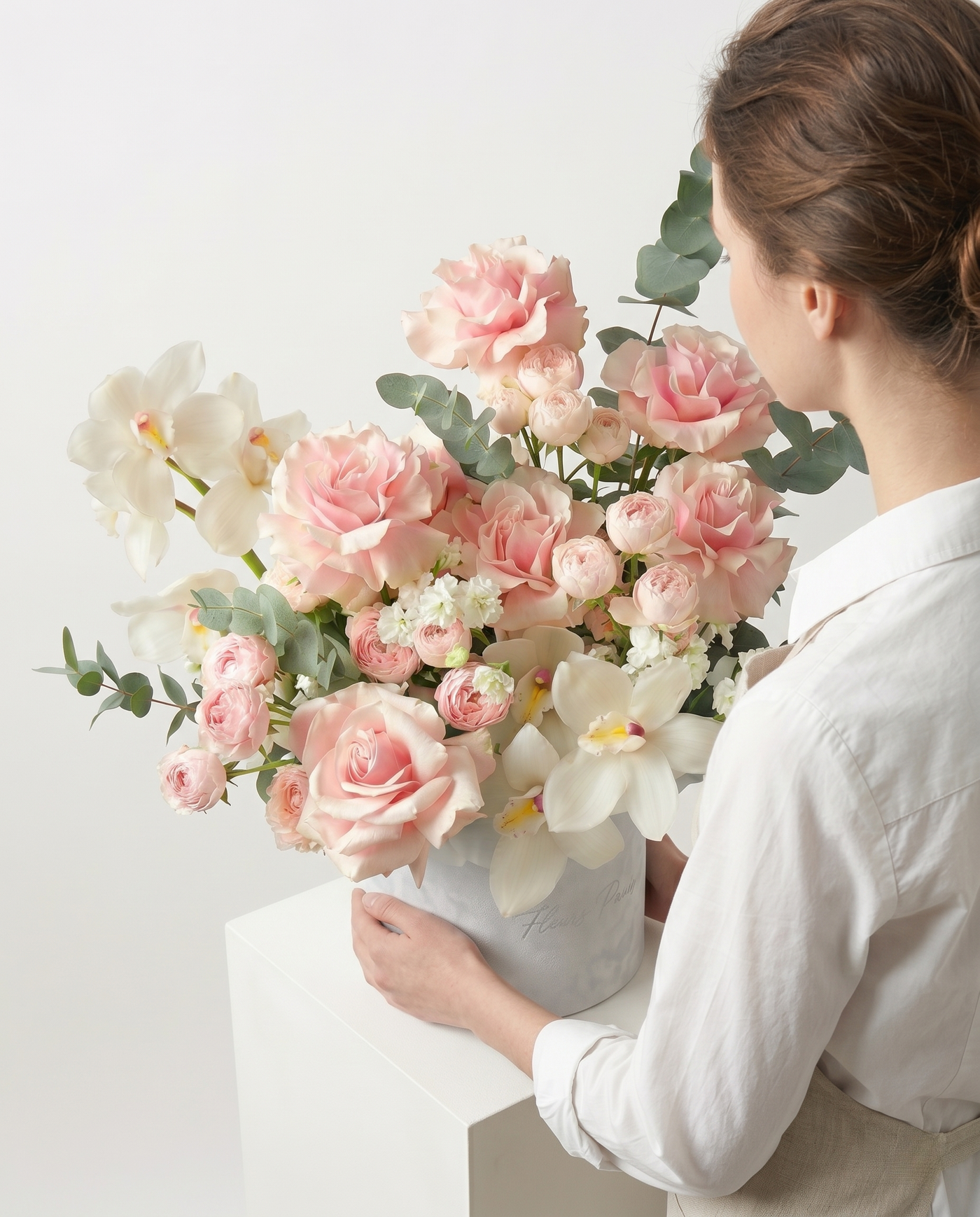 Person holding a large bouquet of pink and white flowers against a light background